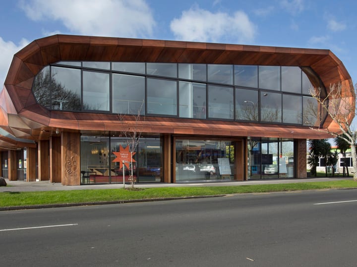 Two-storey timber-clad building with curved roofline, large glazed facade, street frontage