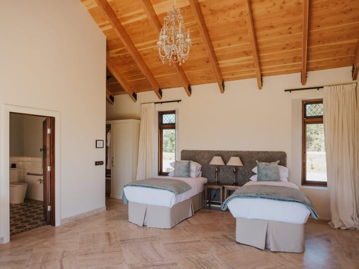 Twin bedroom with timber beam ceiling, upholstered bedheads and leaded windows