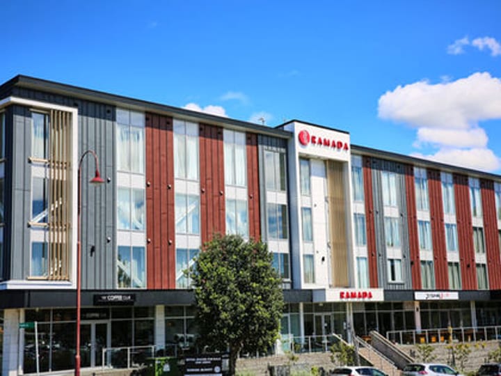 Hotel building exterior with red and grey facade and street-level shops