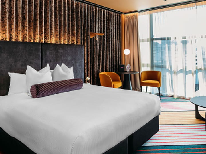 Hotel room with large bed, textured feature wall and floor-to-ceiling window