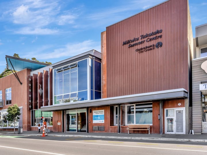 Modern timber-clad community centre building on a town street with hill backdrop