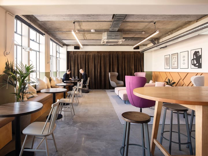 Industrial-style event space with concrete ceiling, banquette seating and soft furnishings
