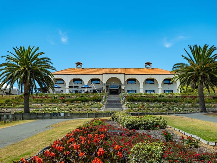 Spanish-style winery building with arched colonnade, red tile roof and formal gardens