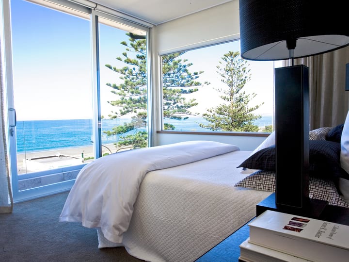Hotel bedroom with dark timber headboard wall and balcony door