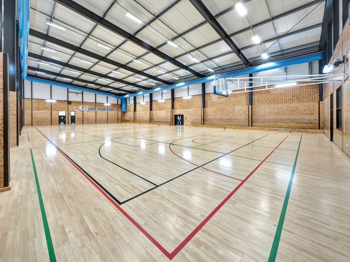 Large indoor sports court with timber floor and blue steel roof structure