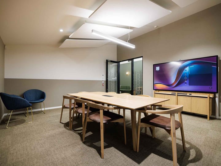 Small meeting room with timber table, chairs, and large wall-mounted screen