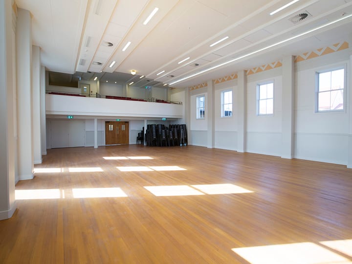 Bright hall interior with polished floor, mezzanine gallery, and decorative frieze on walls