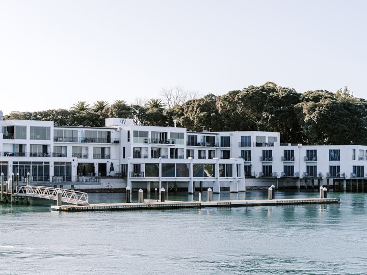 White render building corner over water at golden sunset with bridge in background