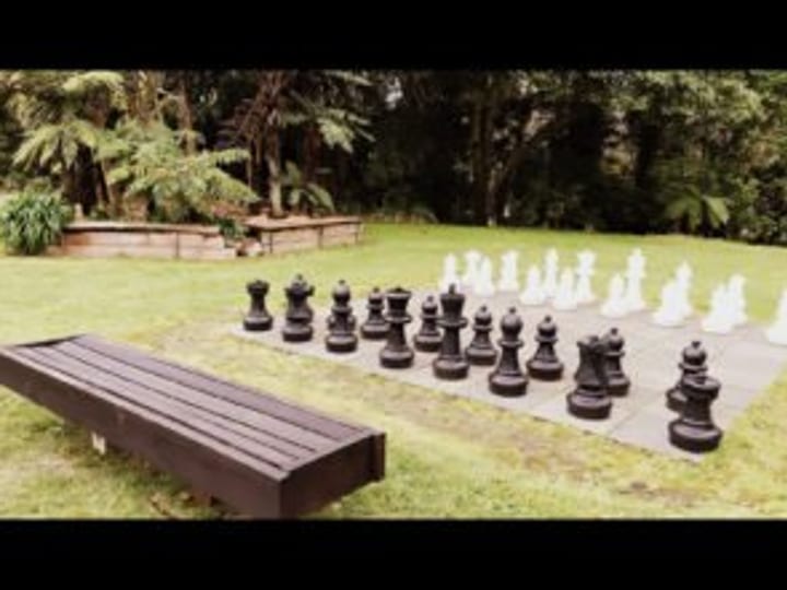 Oversized chess set on a lawn area surrounded by trees