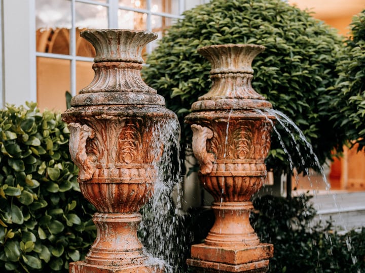 Pair of ornate terracotta fountain urns in a paved garden setting