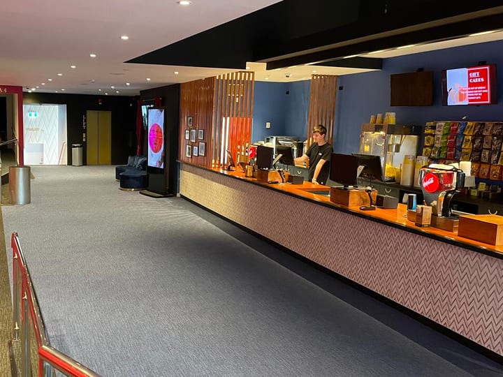 Cinema foyer with ticket counter, red walls, and carpet