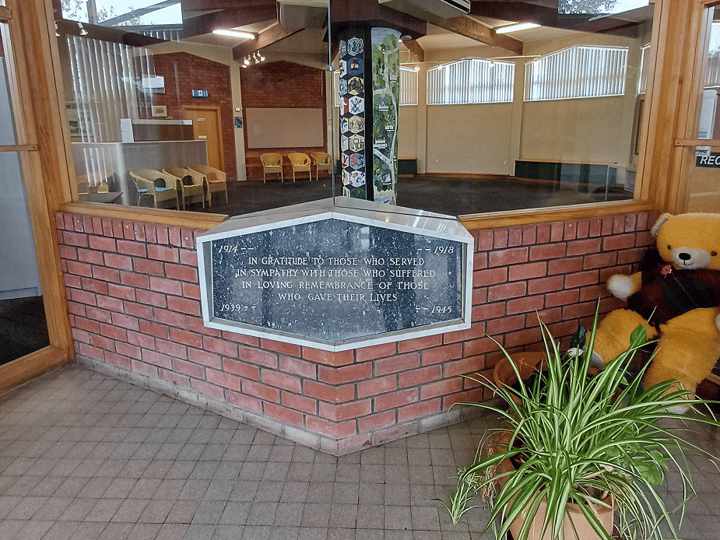 Entry foyer with brick war memorial plaque, planting and view into main hall space