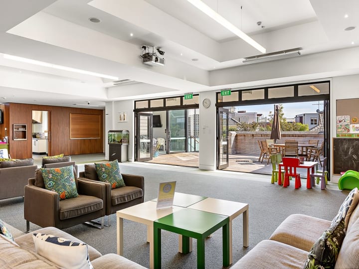 Carpeted lounge with leather sofas, folding doors opening to a timber deck and outdoor seating