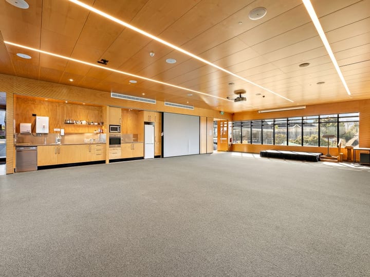 Open hall with timber ceiling panels, kitchenette and large windows