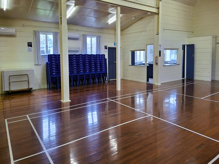 Smaller side room with carpet, folded tables and stacked chairs