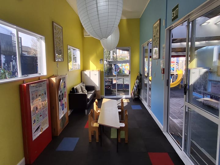 Bright room with yellow walls, children's tables, paper lantern and views to playground