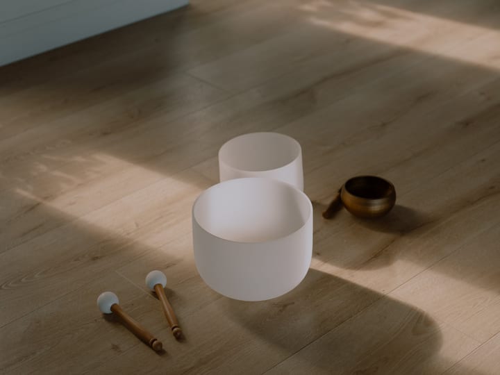 Sunlit timber floor room with singing bowls near open double doors