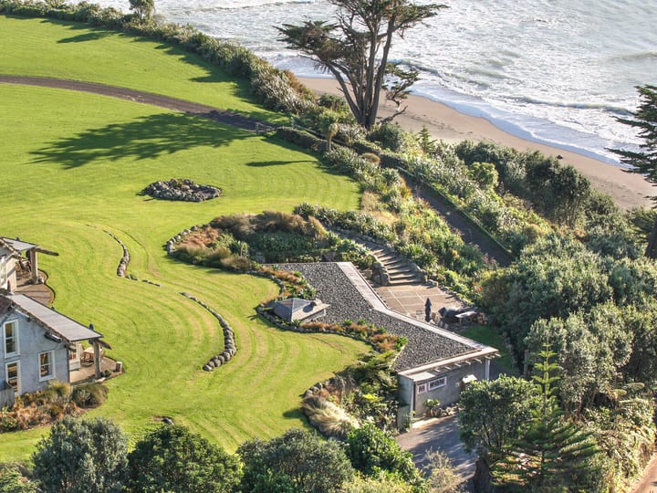 Aerial view of homestead, lawns, and beachfront setting