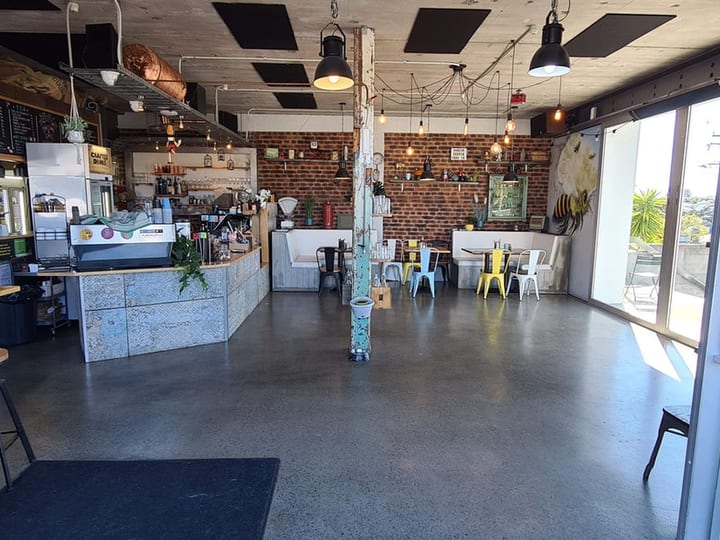 Cafe interior with exposed brick wall, concrete floor, and pendant lights