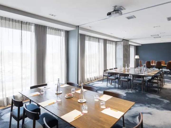 Bright meeting room with U-shape table layout, large windows and projector