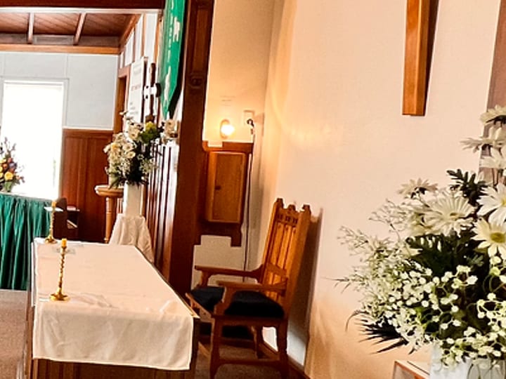 Timber-pewed chapel interior with an altar table, flags, and timber panelling on the walls