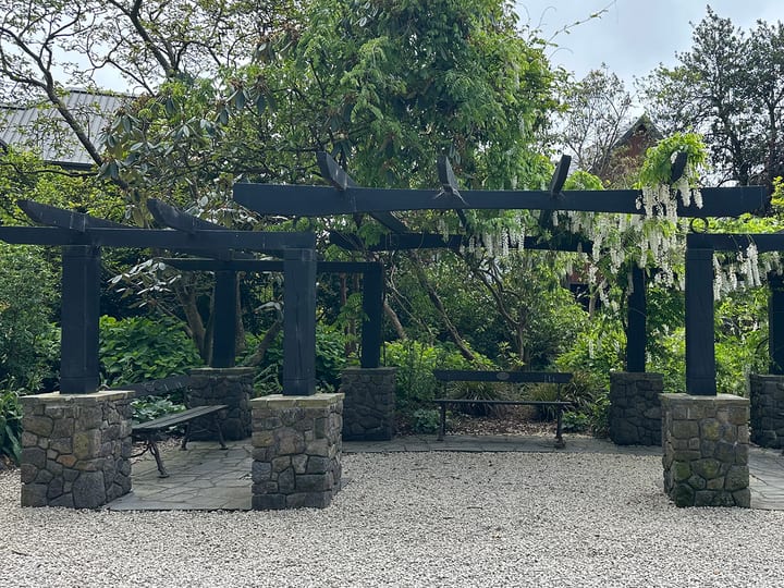 Pergola with stone pillars and hanging flowers in a garden reserve