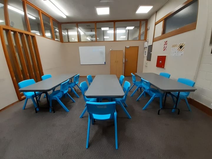 Carpeted room with blue chairs and tables set in rows with whiteboard