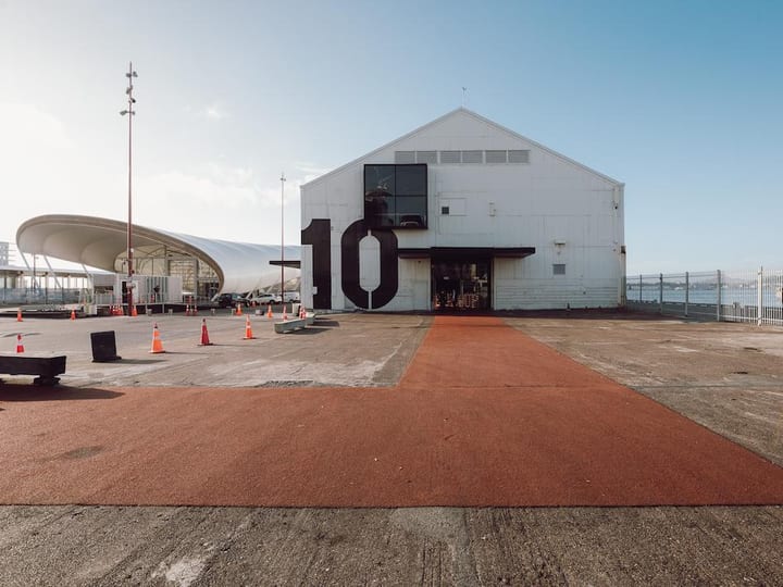 Large white gabled shed building with bold number 10 on facade, waterfront setting