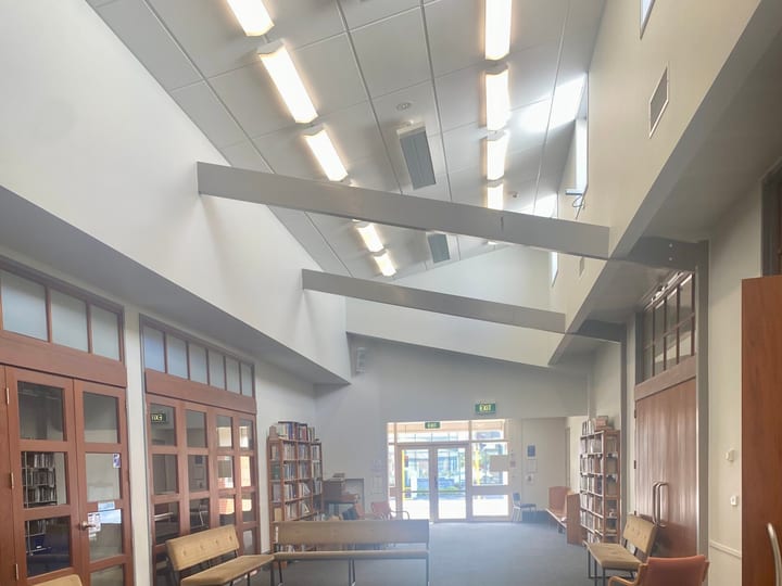 Corridor with timber-panelled walls, bookshelves, and bench seating