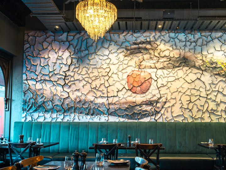 Close-up of decorative stone feature wall with chandelier above velvet banquette seating