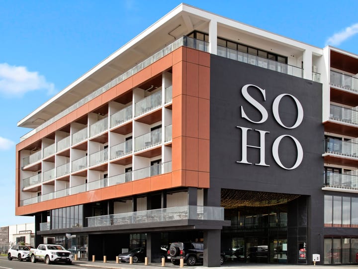 Multi-storey building exterior with terracotta cladding, balconies, and large branded signage, street level
