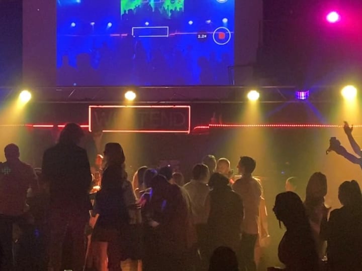 Dark nightclub interior with coloured stage lights and crowd on the dance floor