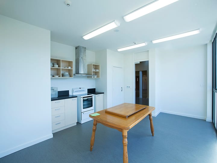Kitchen with stove, rangehood, open shelving and timber table