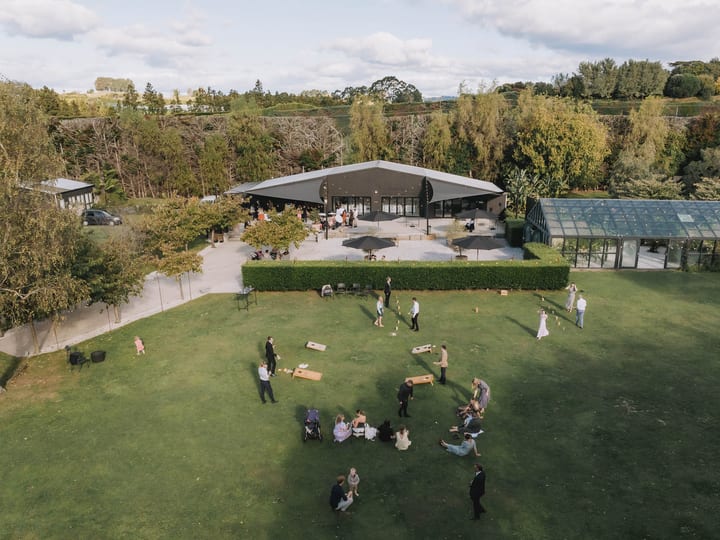 Aerial view of venue pavilion, glass building, and lawn with wedding guests