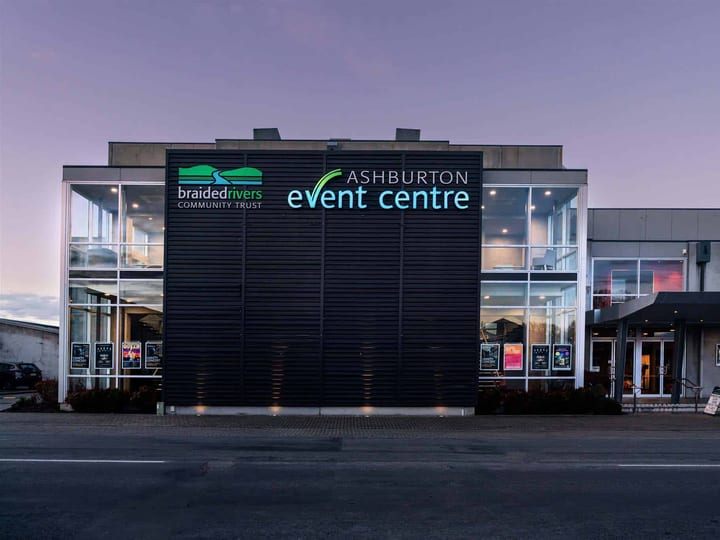 Modern event centre exterior at dusk with illuminated signage on dark cladded facade