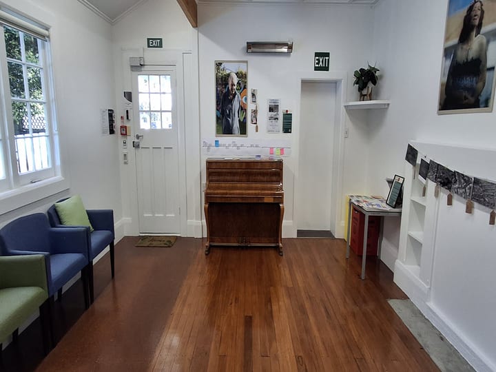 Bright room with timber floors, upright piano and seating area