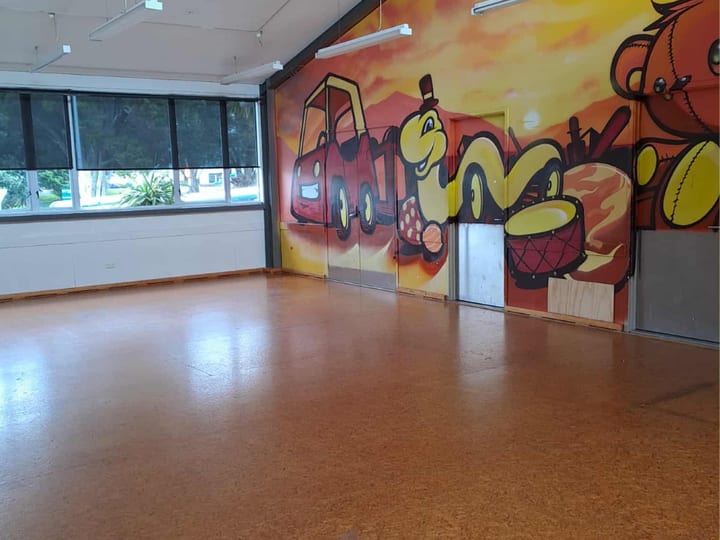 Open room with polished floor and colourful mural across folding partition wall