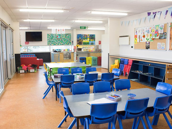 Children's activity room with blue tables, chairs and artwork on walls