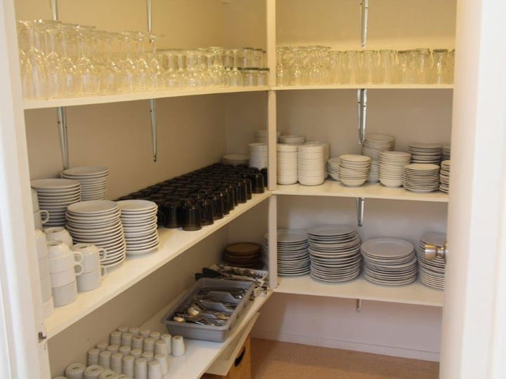 Shelving unit stocked with glasses, plates, bowls and cutlery