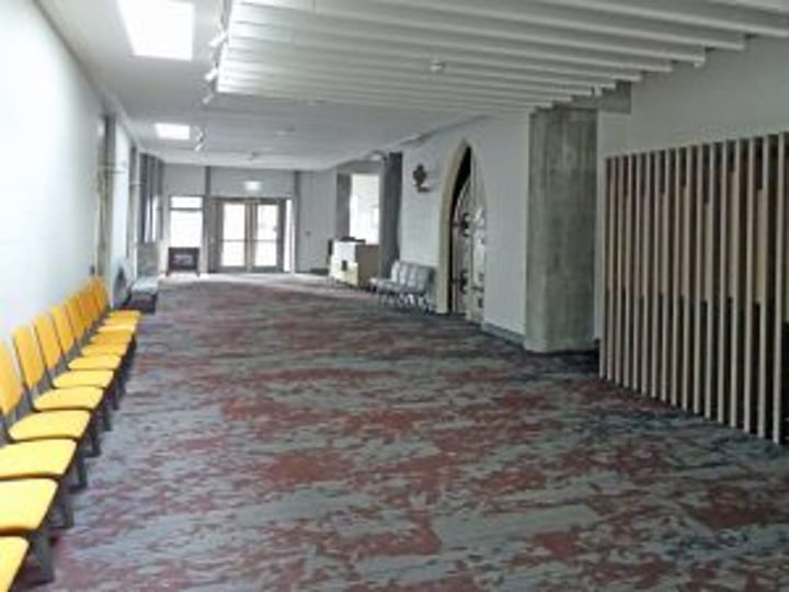 Long corridor with yellow seating along the wall and patterned carpet