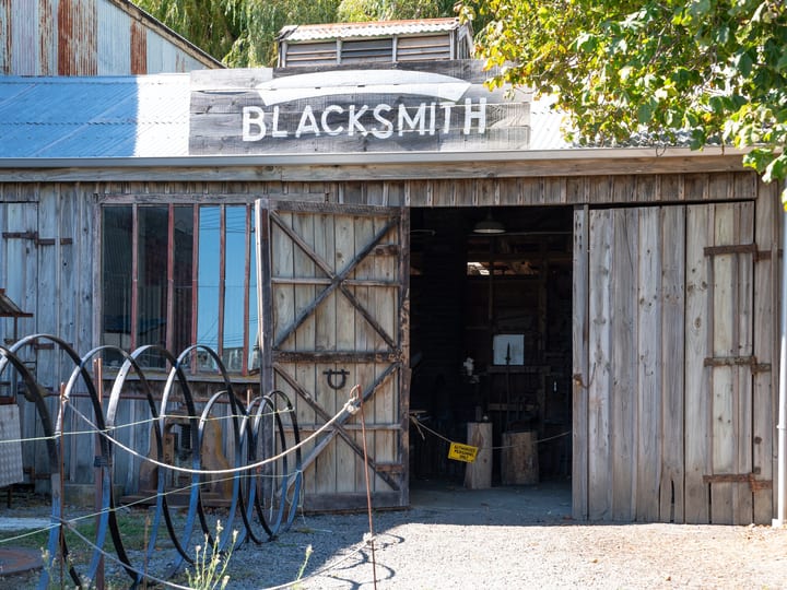 Weatherboard Blacksmith workshop with vintage wheel and open barn doors