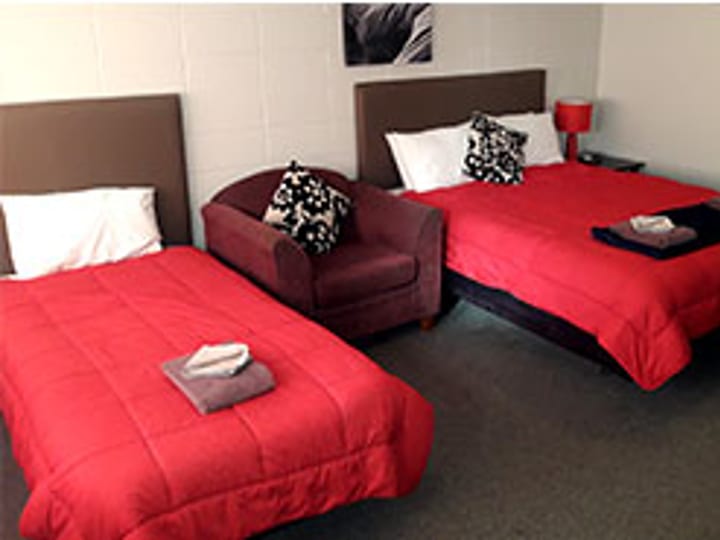 Motel twin bedroom with red bedspreads and armchair