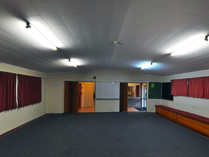 Empty hall with carpet, curtained windows and projection screen at one end