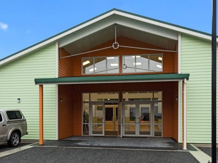 Light green clad hall exterior with signage and carpark