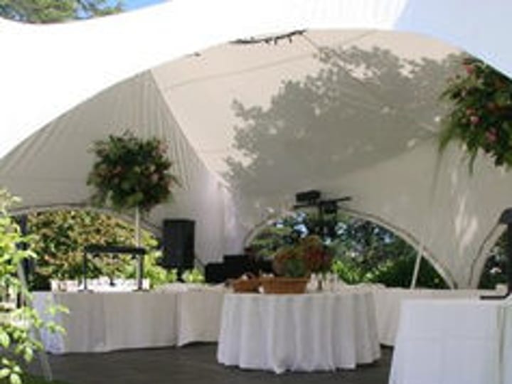 Marquee set with tables and linens on a lawn with floral centrepieces