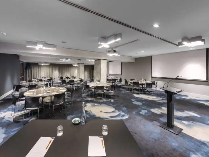 Conference room with patterned carpet, round tables and projector screen