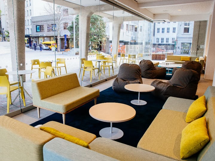Modern ground-floor lounge with floor-to-ceiling glass, modular sofas and outdoor seating beyond