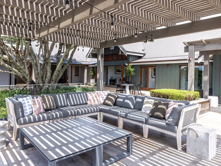 Covered outdoor terrace with timber pergola, grey outdoor sofas and courtyard building surrounds