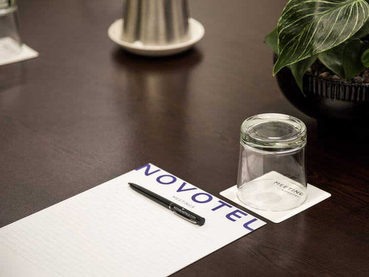 Meeting room with branded notepad, pen and glass on a dark table