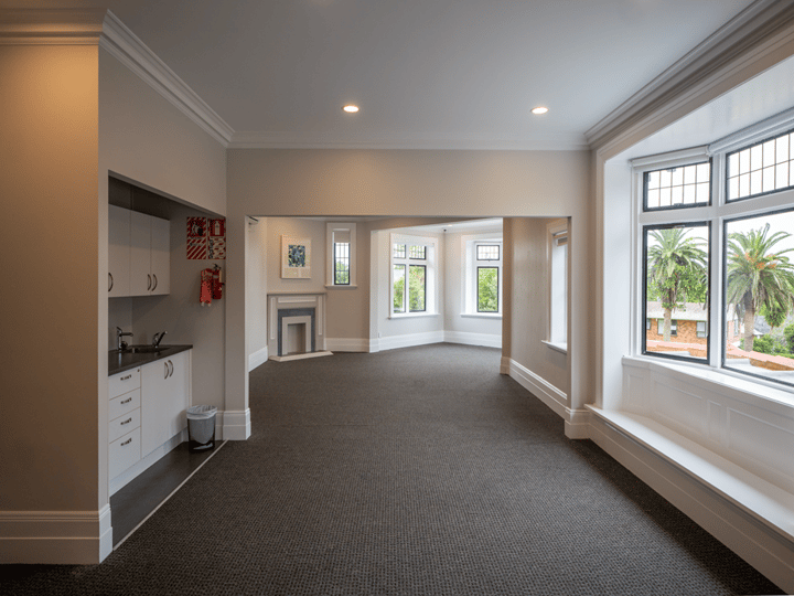 Wide room with leaded bay windows, fireplace alcove and view through to next room